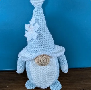 Albie, a pale blue crocheted gonk with a tall pointed hat and a white crocheted snowflake