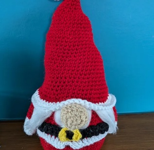 Clement, a crocheted Santa gonk in red with a black belt and gold buckle