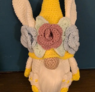 Clover, a yellow crocheted bunny gonk with long ears and a collar of crocheted flowers