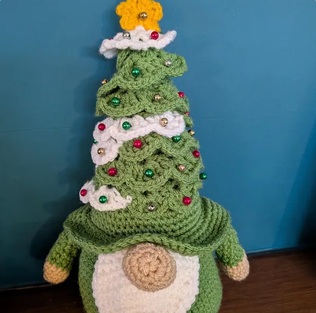Fern, a green crocheted Christmas tree gonk with white garlands, beads and a yellow star on top